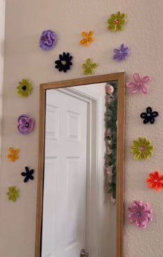 a mirror that has some flowers on the wall above it and is decorated with multicolored paper flowers