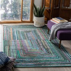 a living room area with a rug, couch and chair in front of a window