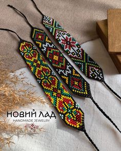 three beaded bracelets are sitting on a table next to some dried grass and a wooden block