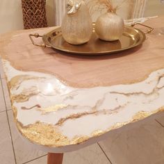 a marble table with two golden vases on it and a gold plate sitting on top