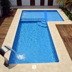 an empty swimming pool in the middle of a wooden decked area with a water spout