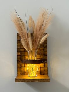 a wooden shelf with two vases and some dry grass in it on the wall