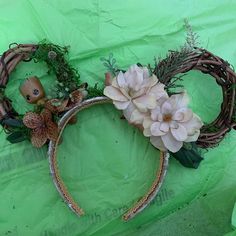 a headband with flowers and plants on it sitting on a green cloth covered surface