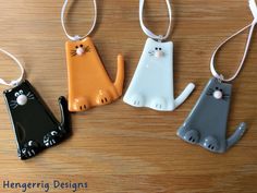 three ceramic cats are hanging from strings on a table