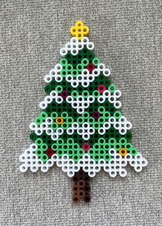 a christmas tree made out of perler beads on a gray surface with white circles around it