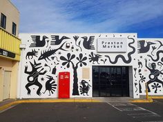 a white building with black designs on it's side and a red door in front