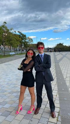 a man and woman dressed up in formal wear posing for a photo on the sidewalk