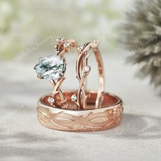 two wedding rings sitting on top of each other next to a pine cone with leaves