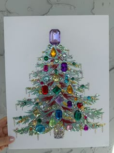 a hand holding up a card with a christmas tree made out of jeweled stones