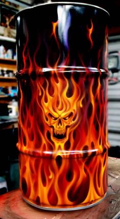 a large metal barrel with flames and a skull on the front is sitting on a wooden table