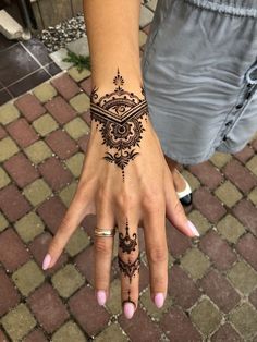 a woman's hand with a henna tattoo on her left wrist and fingers