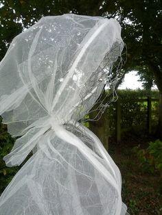 there is a white net wrapped around the head of a statue in front of some trees