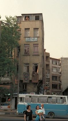 two people sitting on a bench in front of an old building with many windows and balconies