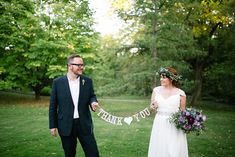 a bride and groom holding a thank you banner