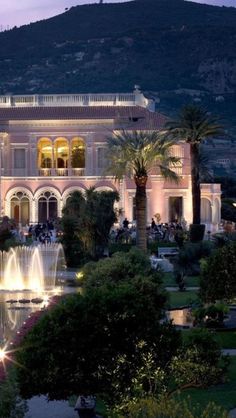 a large building with fountains in front of it and trees around the perimeter at night