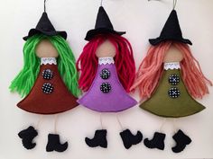 three felt witches hanging from hooks on a wall