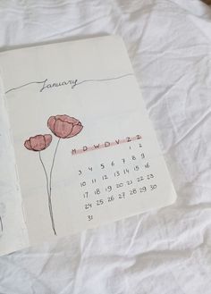 a calendar with flowers drawn on it sitting on a sheet of white paper next to a pen