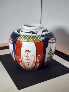 a colorful vase sitting on top of a black and white checkered tablecloth covered floor