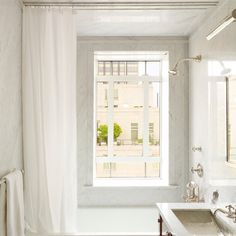 a bathroom with a sink, mirror and bathtub in front of a large window