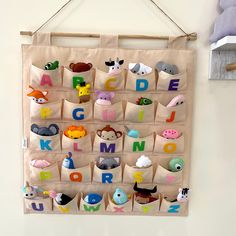 a wall hanging with stuffed animals and letters in the shape of bags on it's sides