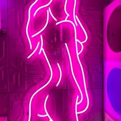 a neon sign with a woman standing in front of it