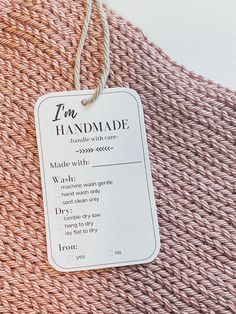 a tag that is on top of a pink knitted blanket with the words true handmade written in it