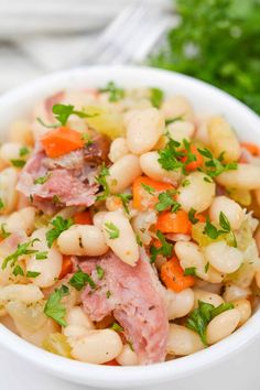 a white bowl filled with beans and ham