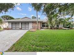 a house with palm trees in front of it and grass on the side of the road