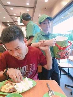 a man sitting at a table eating food with chopsticks in front of him