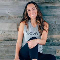 a woman is sitting on the floor with her leg up and smiling at the camera