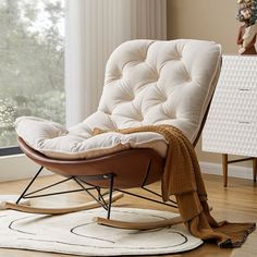 a white rocking chair sitting on top of a hard wood floor next to a window