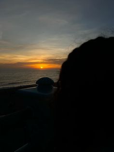 the sun is setting over the ocean as people watch