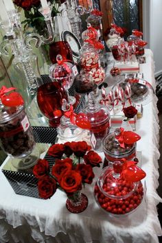 a table topped with lots of candy and candies next to vases filled with flowers