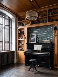 a room with a piano, bookshelf and window