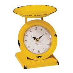 a yellow clock sitting on top of a stand with black dots around the face and hands