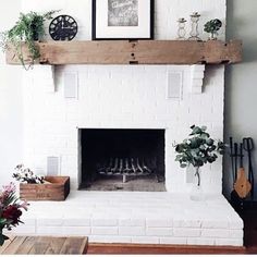 a white brick fireplace with potted plants on the mantel and pictures above it