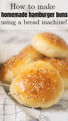 three homemade hamburger buns sitting on top of a white plate with text overlay reading how to make homemade hamburger buns using a bread machine