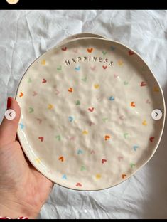 a person holding a plate with the words happiness on it and hearts painted on it