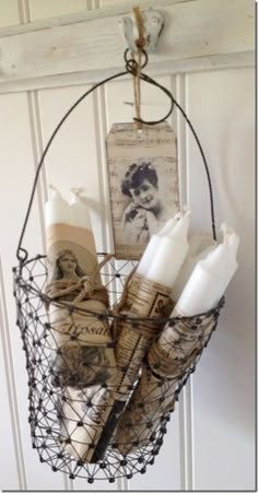 a wire basket with candles and pictures hanging from the side on a door hanger