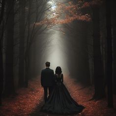 a man and woman standing in the middle of a forest with leaves on the ground