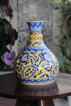 a blue and yellow vase sitting on top of a wooden table