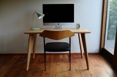 a wooden desk with a computer on it and a chair in front of the monitor