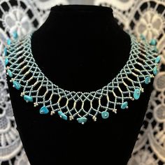 a necklace with turquoise stones and silver beads on a black mannequin neckline