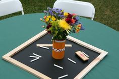 a vase filled with flowers sitting on top of a blackboard covered in pencils