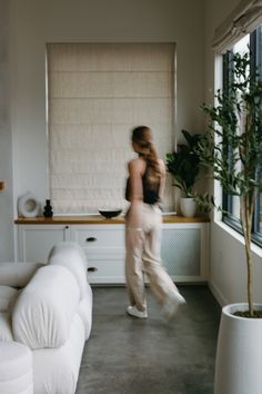 a woman walking through a living room next to a white couch