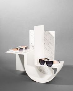 two pairs of sunglasses sitting on top of a white display case with marbled surface