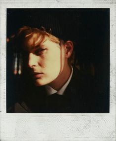 a young man with red hair wearing a black jacket and bow tie looking at the camera