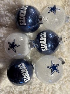 three glass christmas ornaments with the word cowboys on them are laying on a white carpet