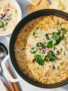 a bowl of soup with tortilla chips on the side and other food items