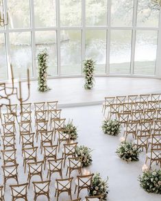 an indoor wedding venue with rows of chairs and floral arrangements